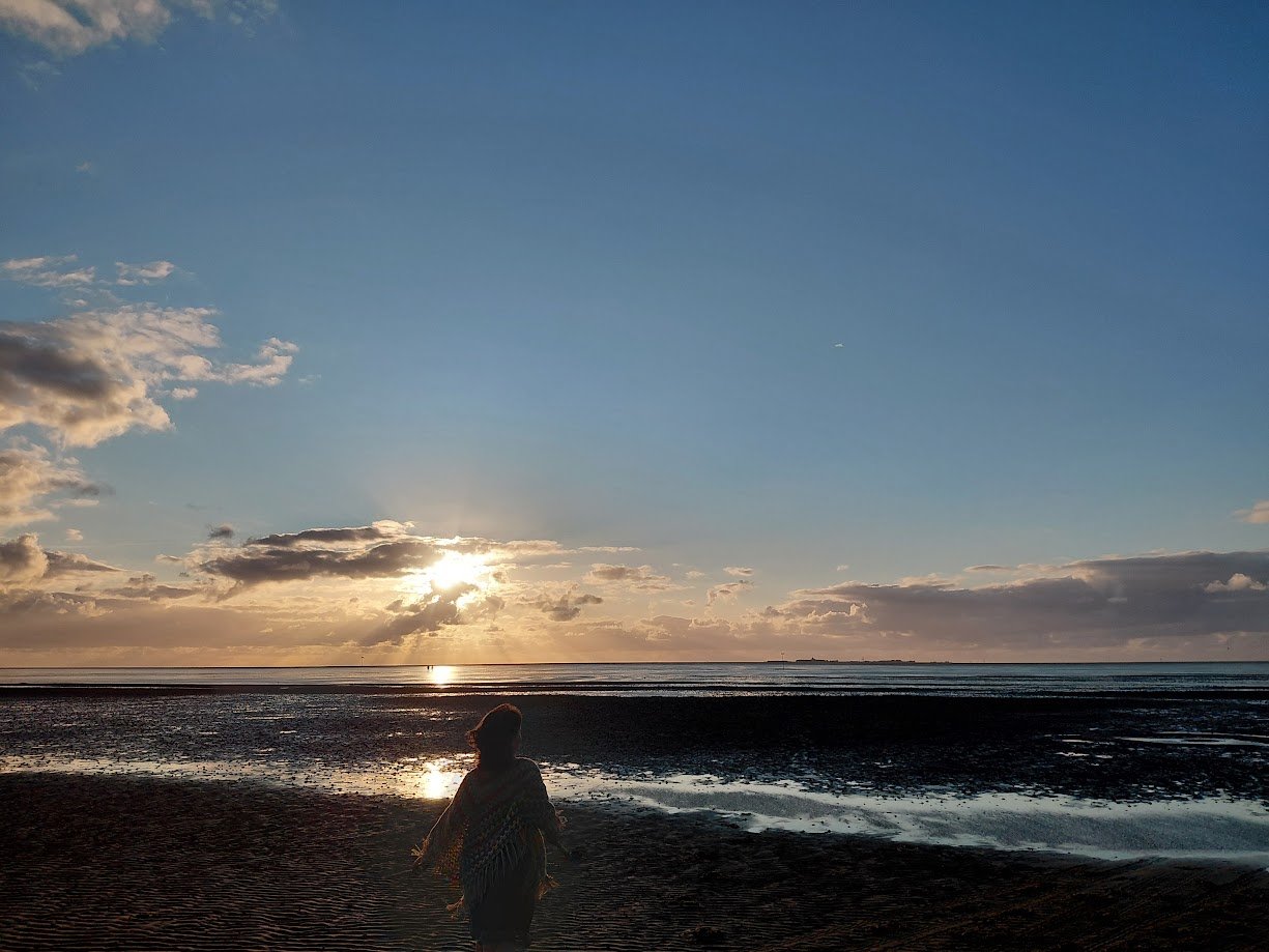 Kid at falling tide at North Sea at sunset.