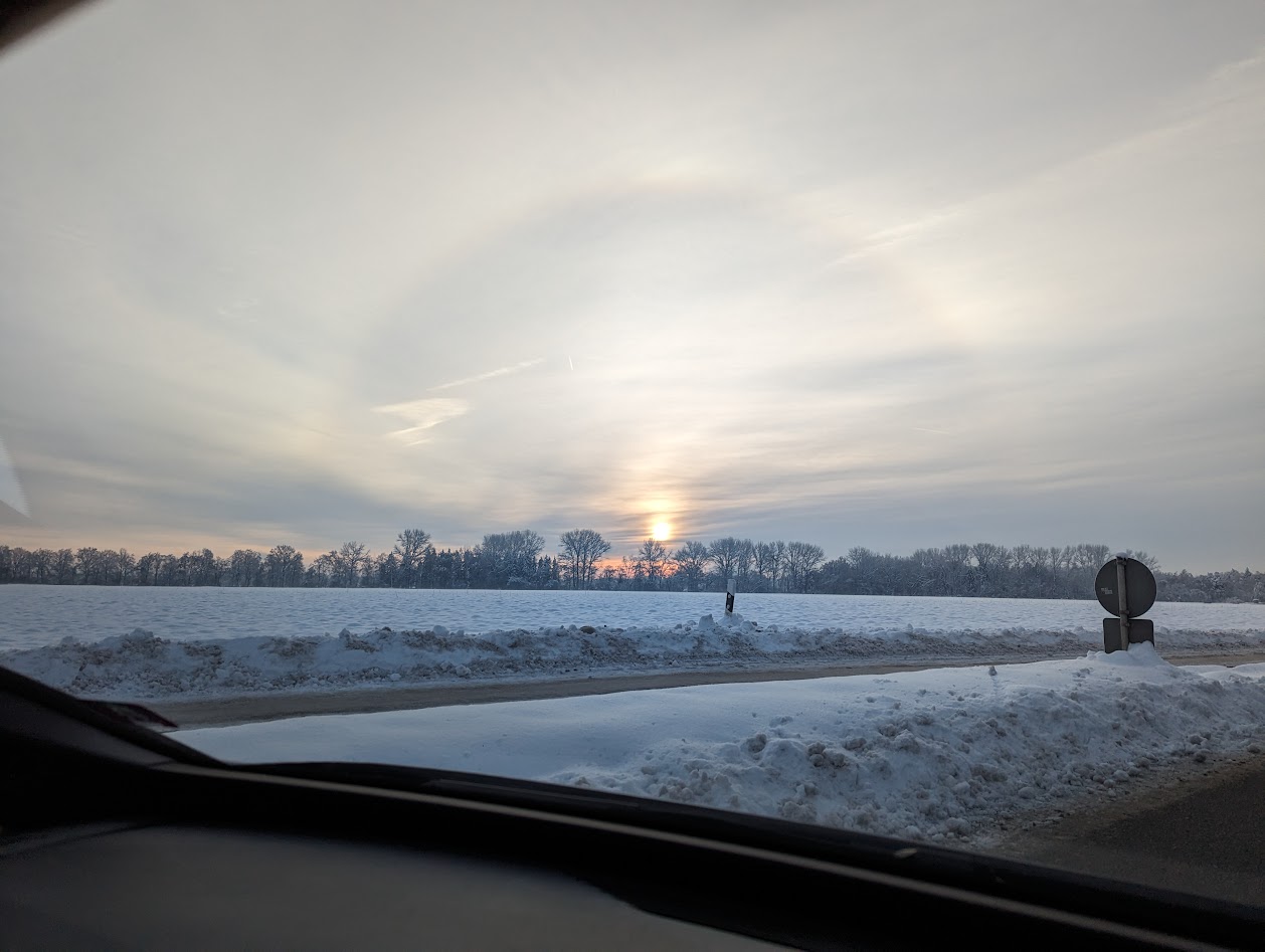 Snow with halo around the sun seen from a car.