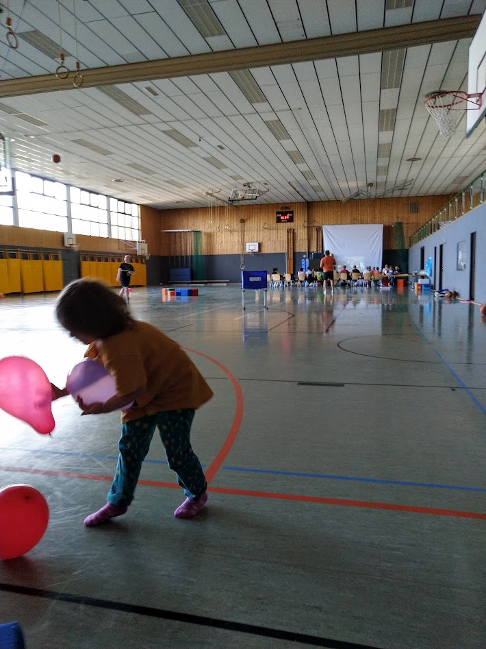 Basketballgame in the background, playing with balloons.