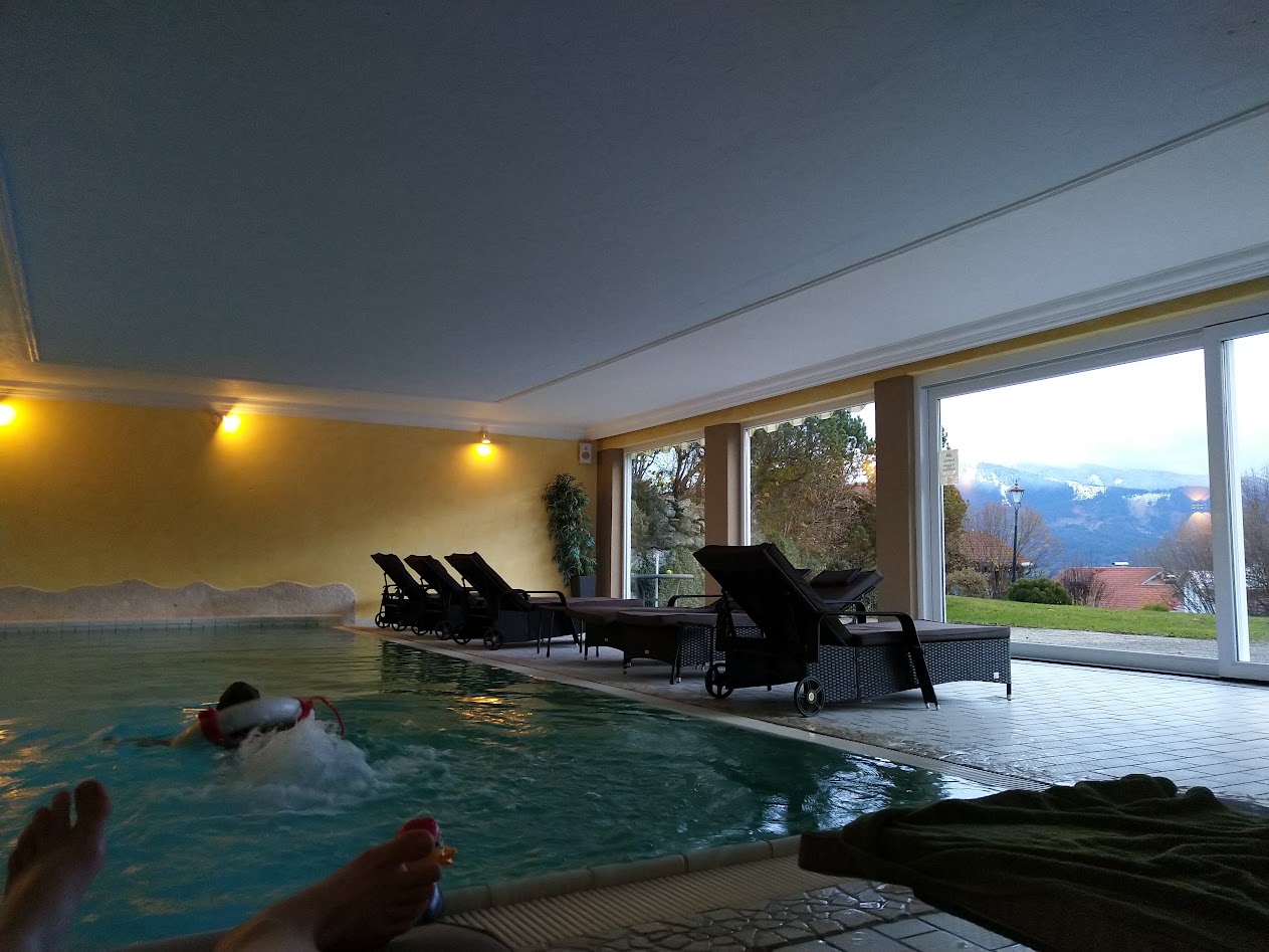 Girl in a pool, someone outside and mountains in the background.