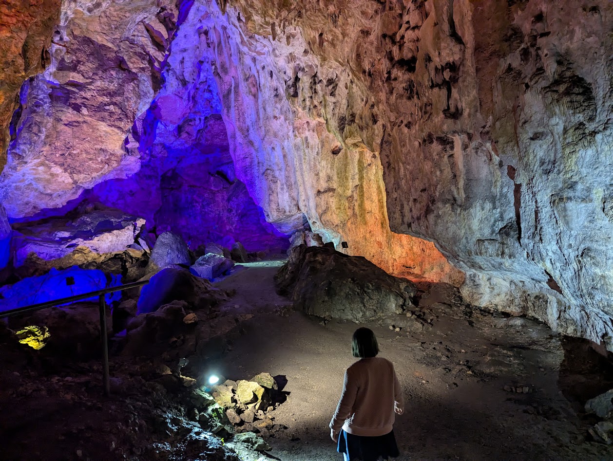 Natural cave illuminated with colours and the little one in the foreground.